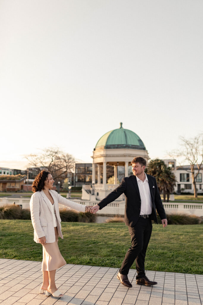 Engagement photography session in Christchurch CBD capturing a couple walking hand in hand during golden hour, photographed by Lavender Turner Photography.