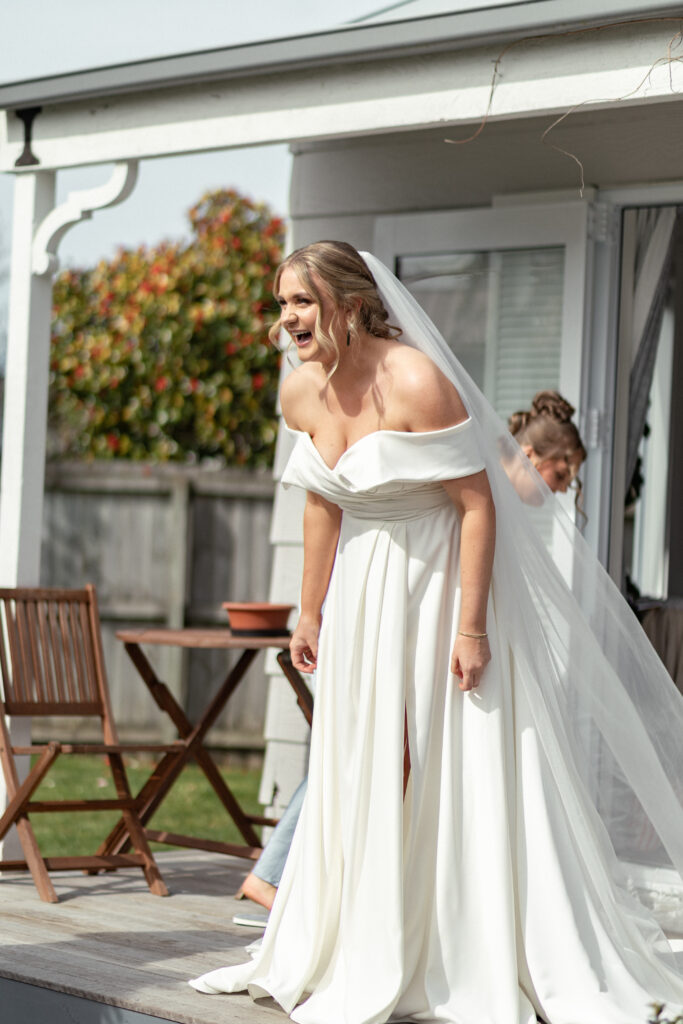Documentary-style wedding photograph capturing a candid, joyful reaction of the bride in Christchurch moments before the ceremony.